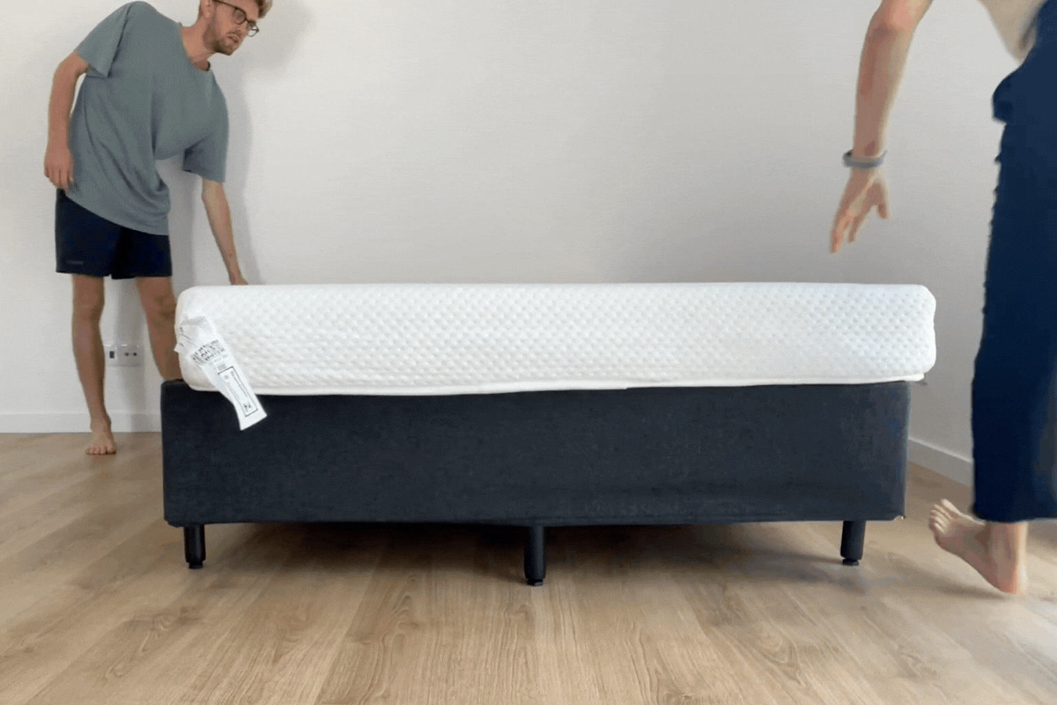 Vídeo curto de duas pessoas girando um colchão horizontalmente sobre uma base box